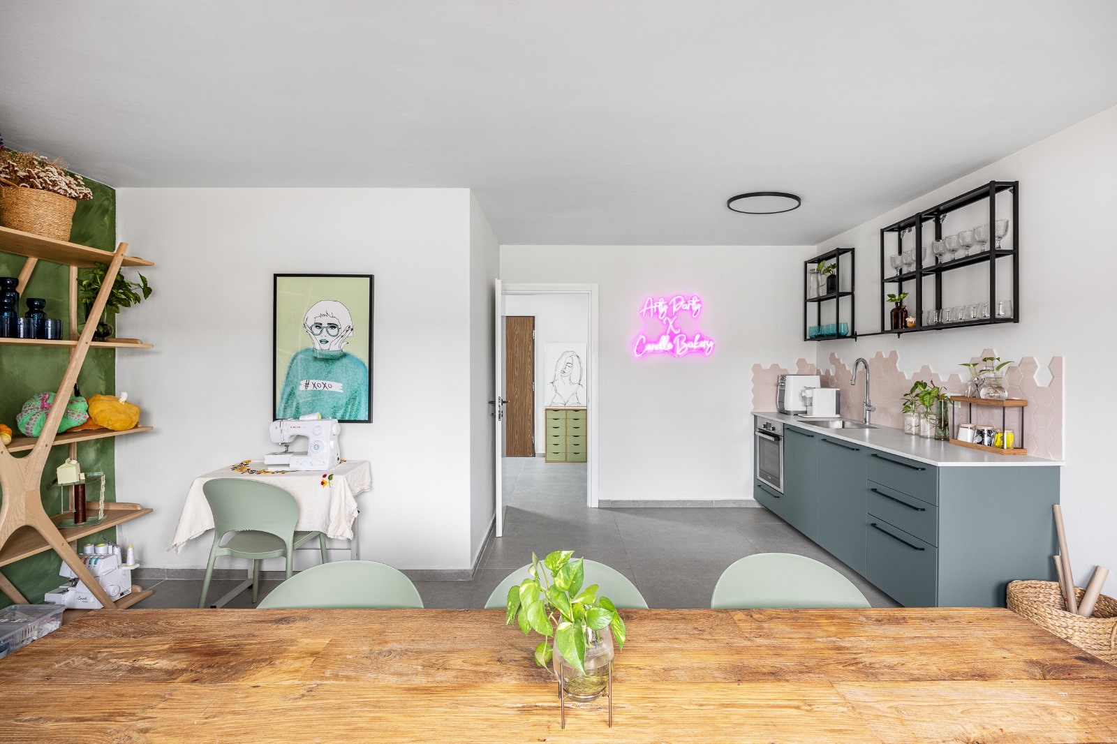 מבט כולל על סטודיו ArtyParty — חדר יצירה עם מטבח פתוח, מדפי עץ, וכיסאות ירוקים